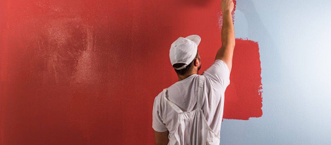 Young man painting wall with roller